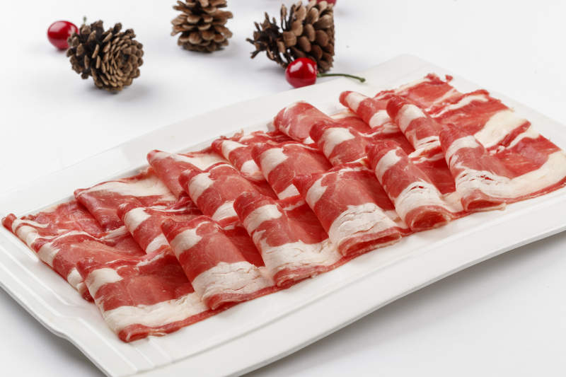 白色背景上的长瓷盘装的涮肉食材羊肉片图片