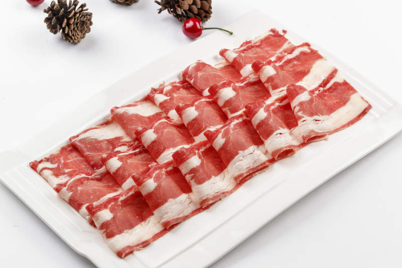 白色背景上的长瓷盘装的涮肉食材羊肉片图片