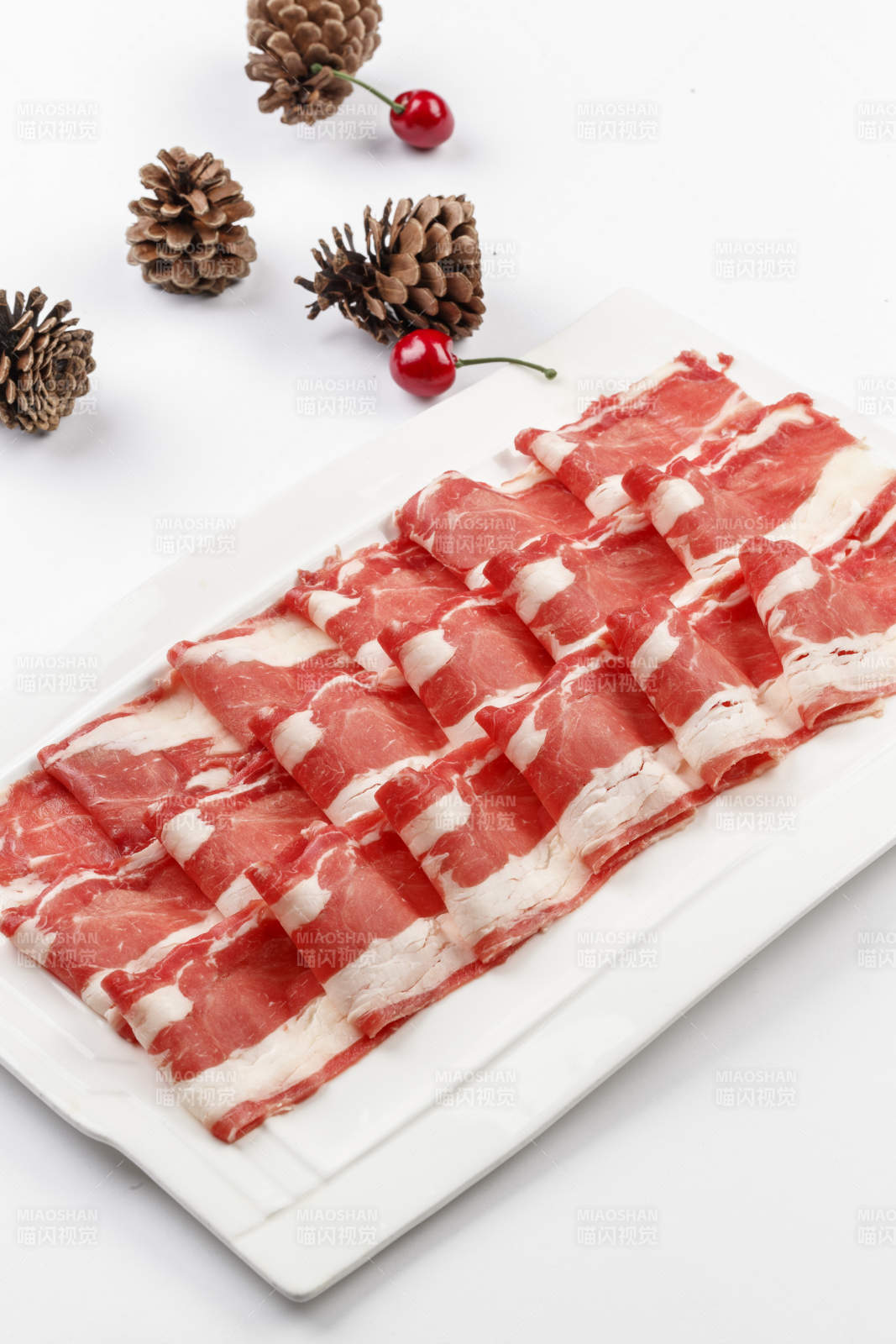 白色背景上的长瓷盘装的涮肉食材羊肉片图片