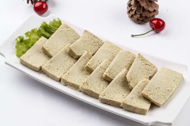白色背景上的长瓷盘装的火锅食材冻豆腐图片