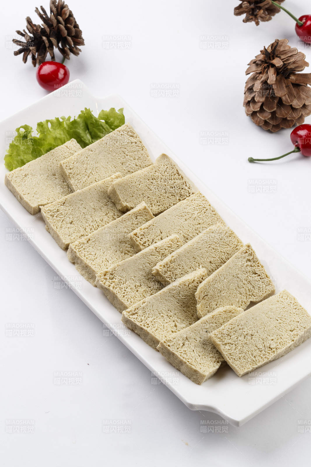 白色背景上的长瓷盘装的火锅食材冻豆腐图片