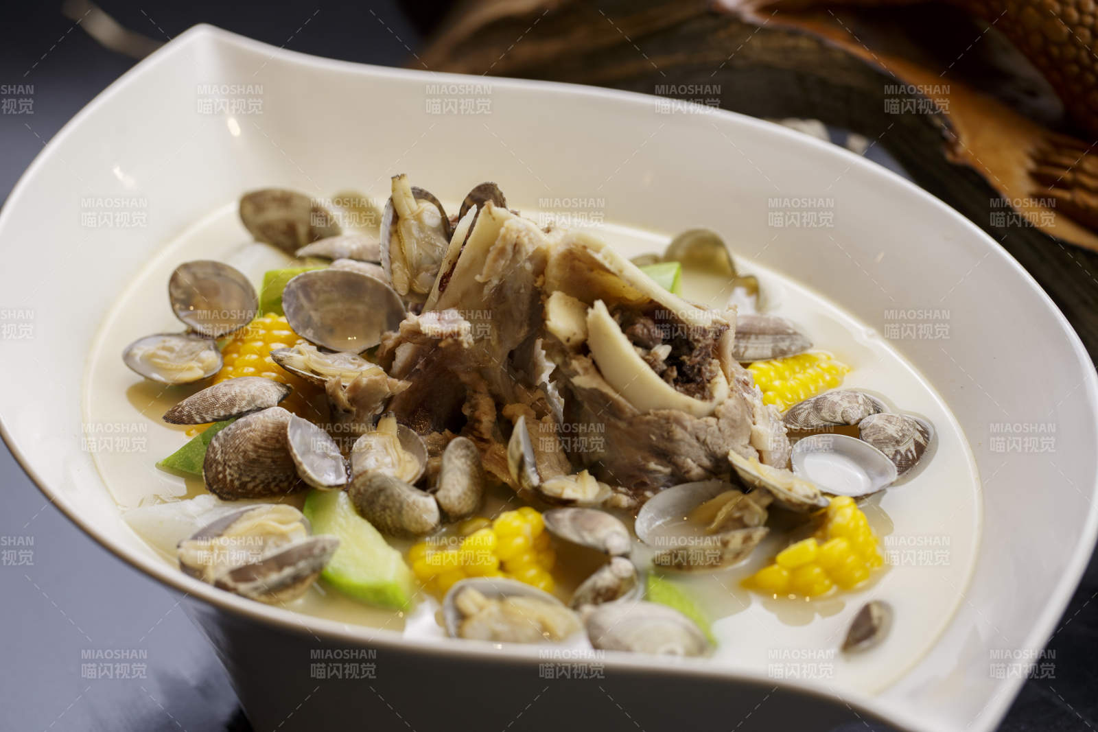 树叶形瓷盘装的奶汤棒骨花蛤炖时蔬图片