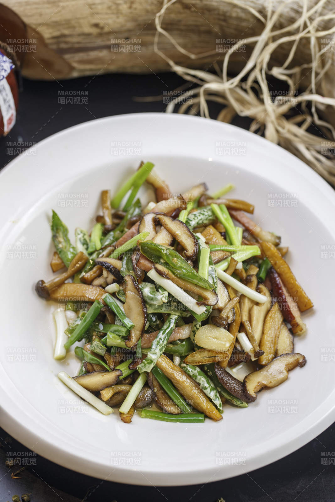 圆形白色瓷盘装的腊肉小炒山珍菌图片