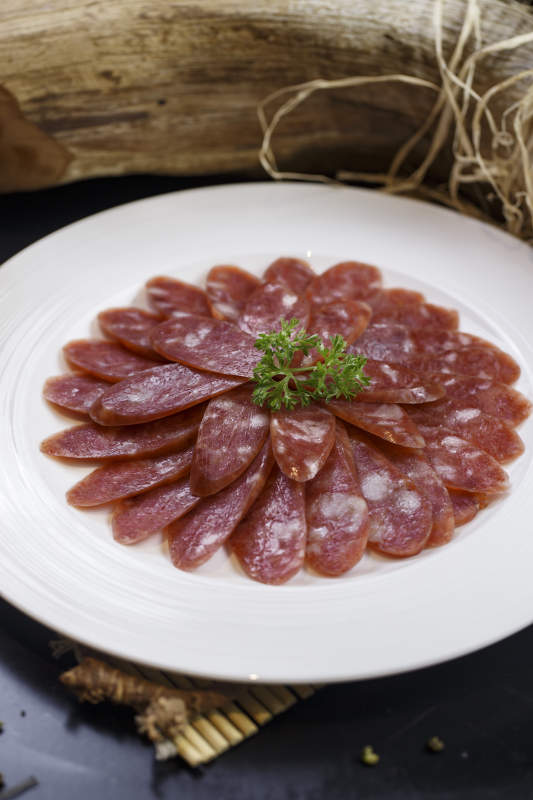 圆形白瓷盘装的川味甜腊肠图片