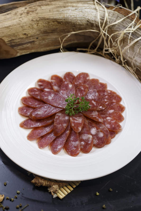 圆形白瓷盘装的川味甜腊肠图片