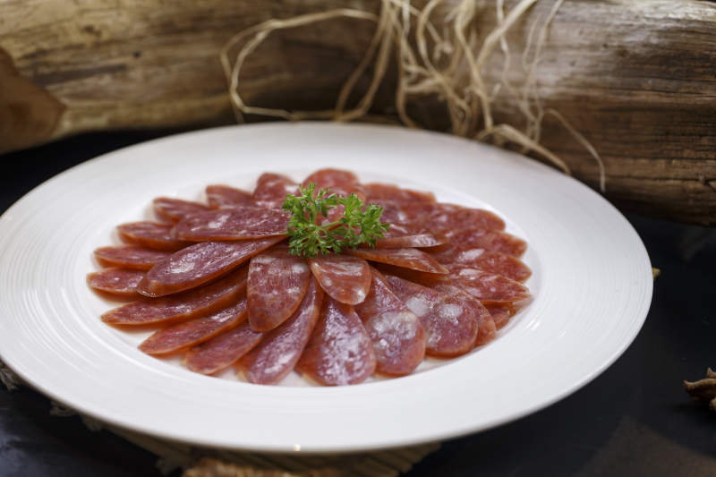 圆形白瓷盘装的川味甜腊肠图片