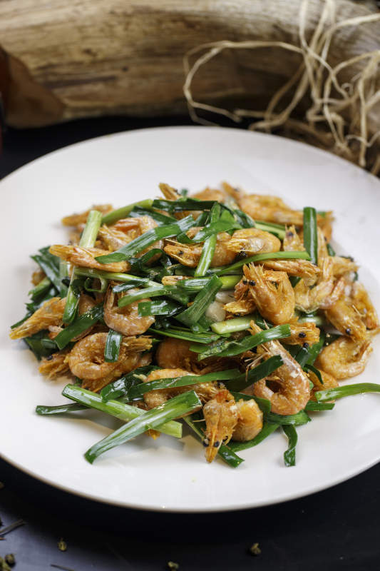 圆形白瓷盘装的韭菜炝炒小河虾图片