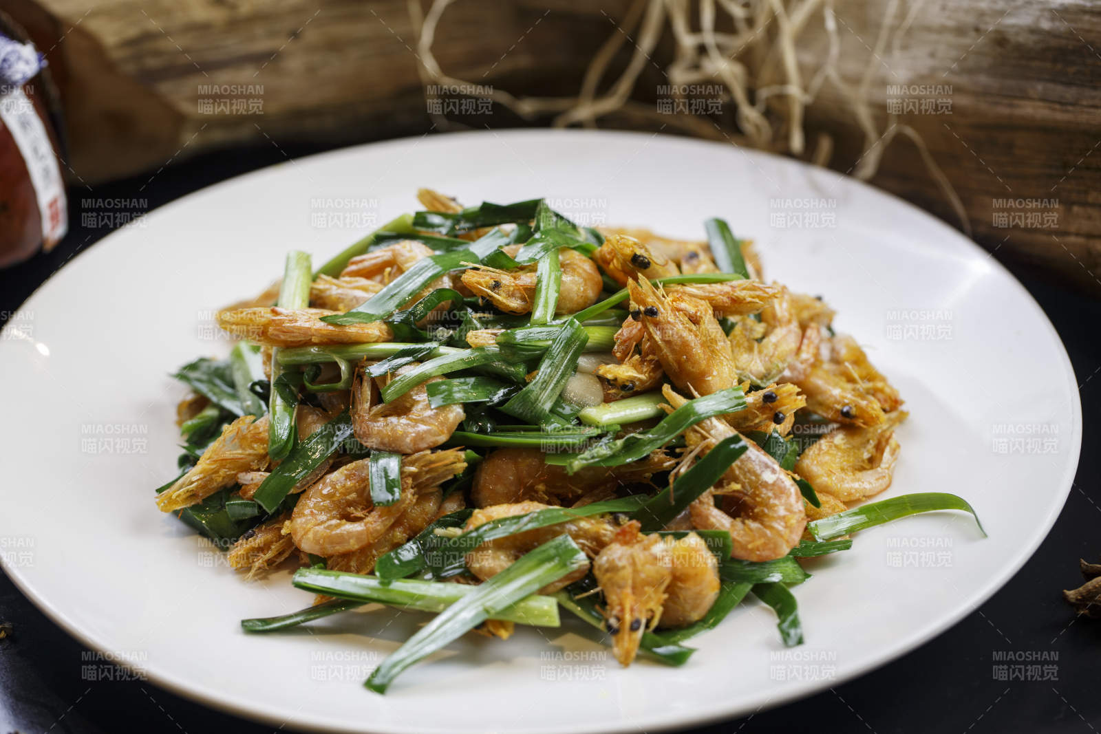 圆形白瓷盘装的韭菜炝炒小河虾图片