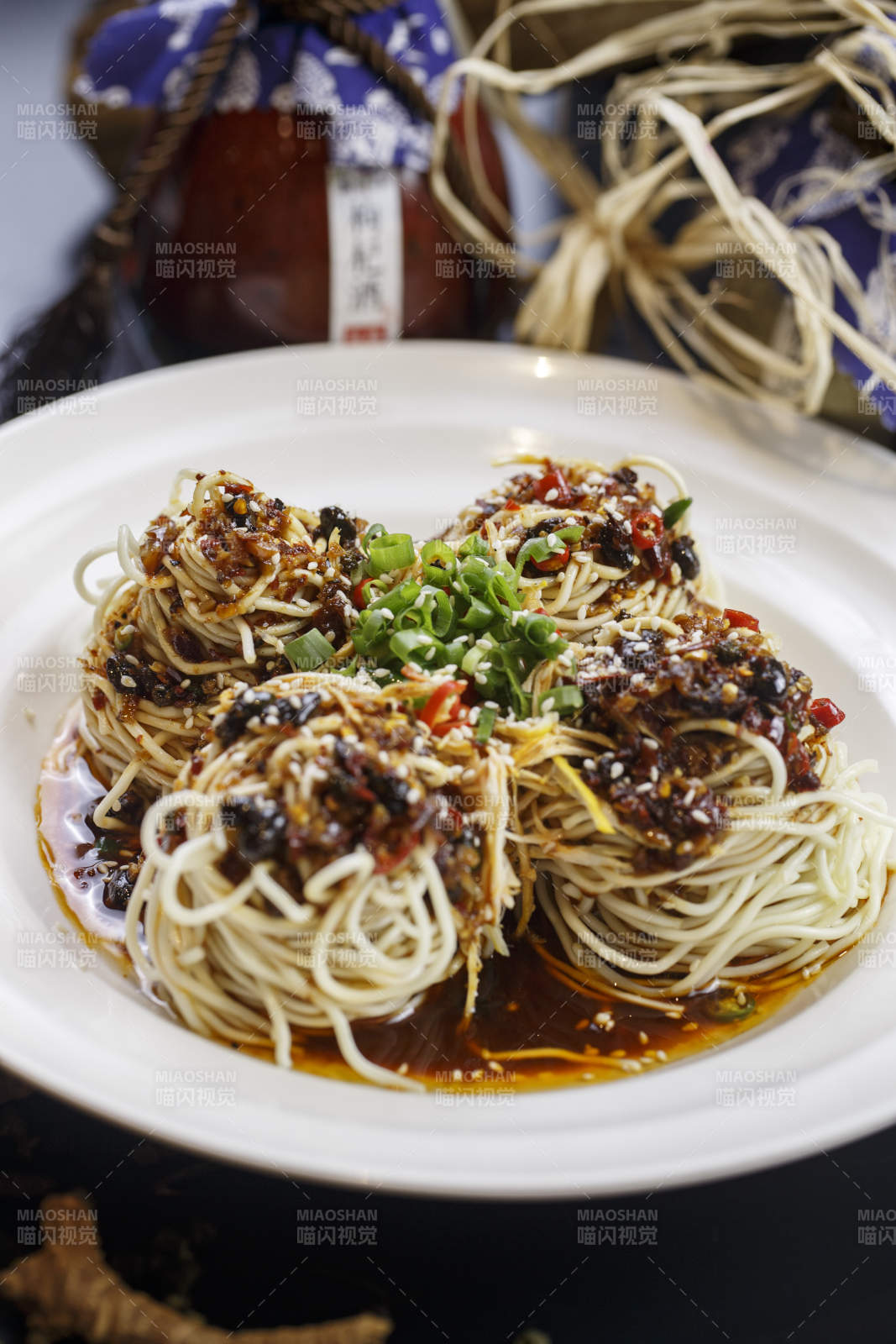 圆形白瓷盘装的麻辣鸡丝担担面图片