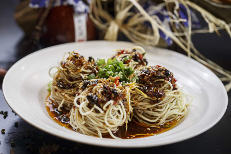 圆形白瓷盘装的麻辣鸡丝担担面图片