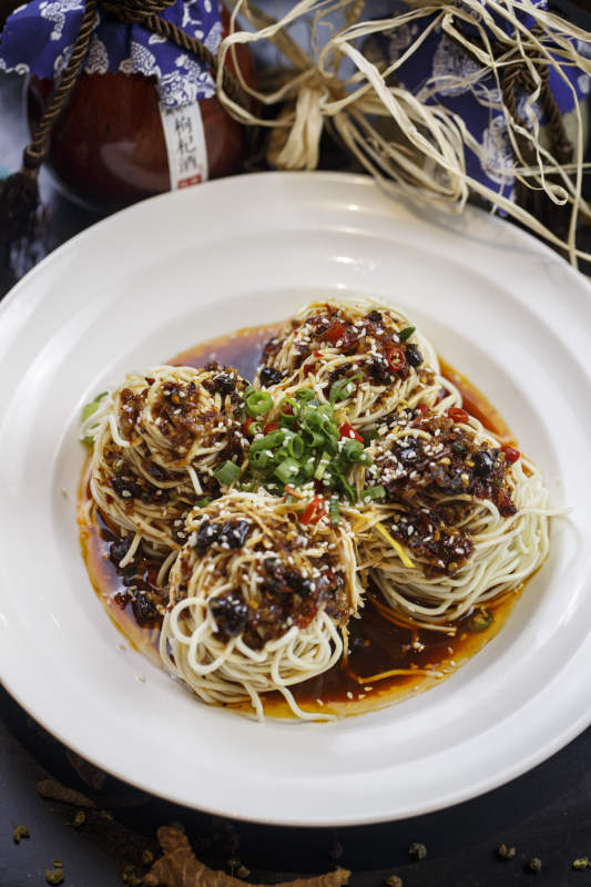 圆形白瓷盘装的麻辣鸡丝担担面图片