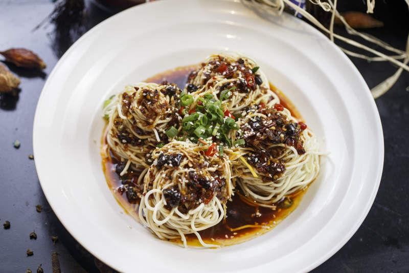 圆形白瓷盘装的麻辣鸡丝担担面图片