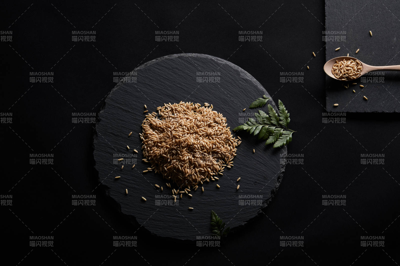 黑色青石板上的木质勺子装的燕麦米摆放在黑色背景中图片