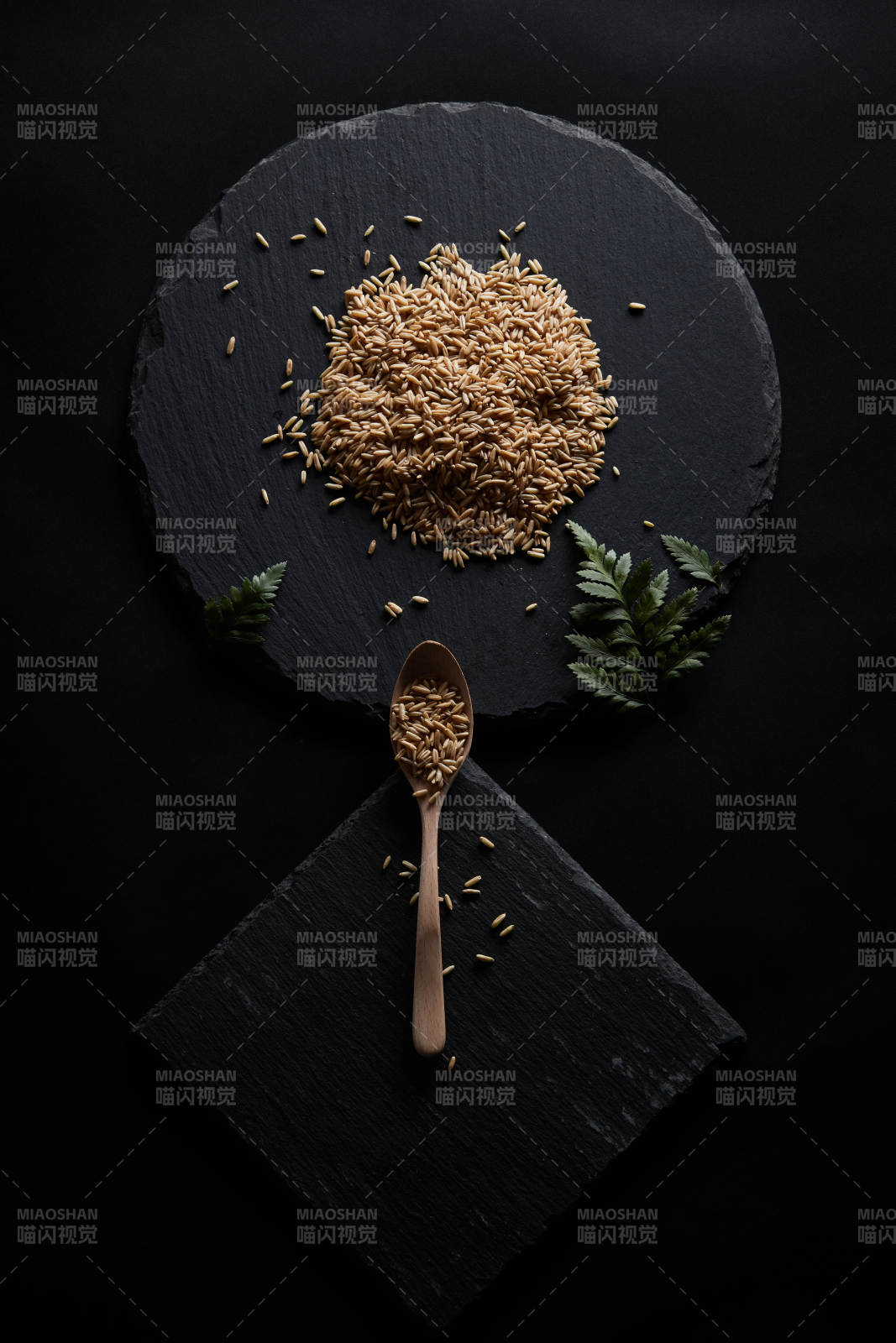 黑色青石板上的木质勺子装的燕麦米摆放在黑色背景中图片