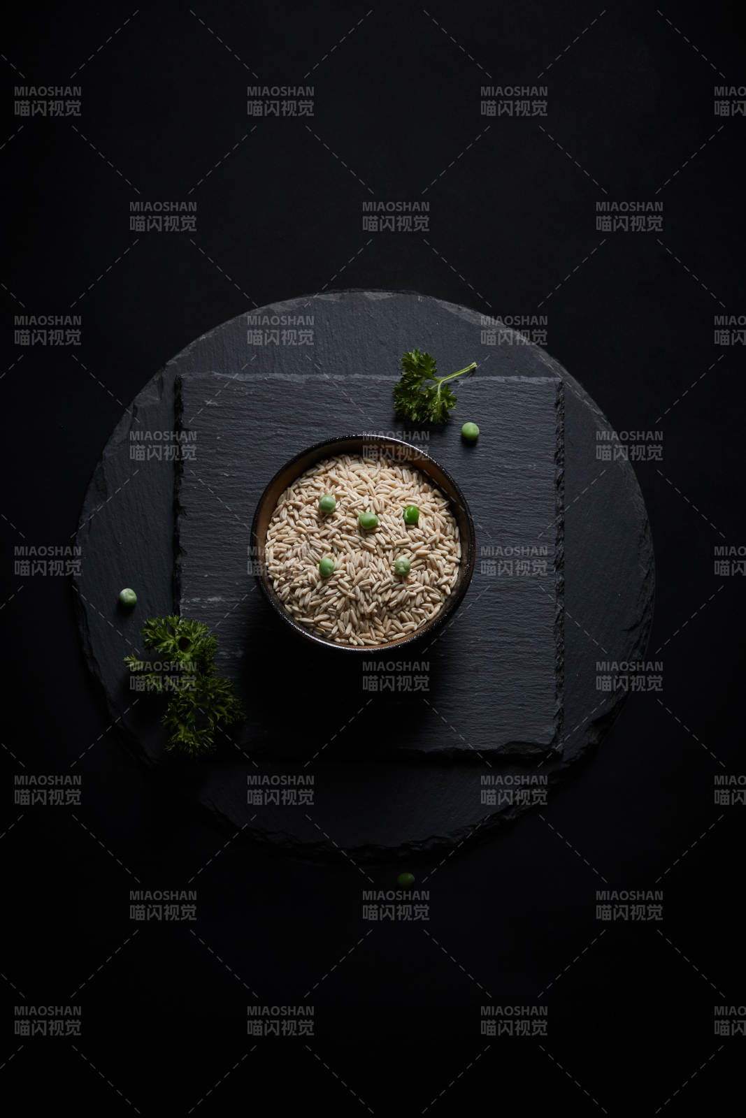 黑色青石板上的木质勺子装的燕麦米摆放在黑色背景中图片