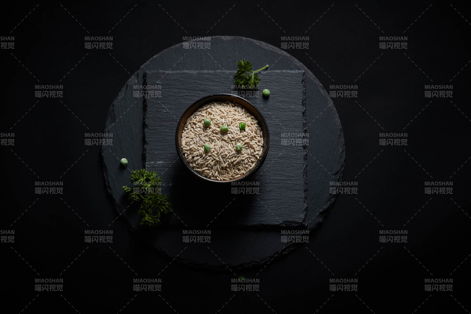 黑色青石板上的木质勺子装的燕麦米摆放在黑色背景中图片