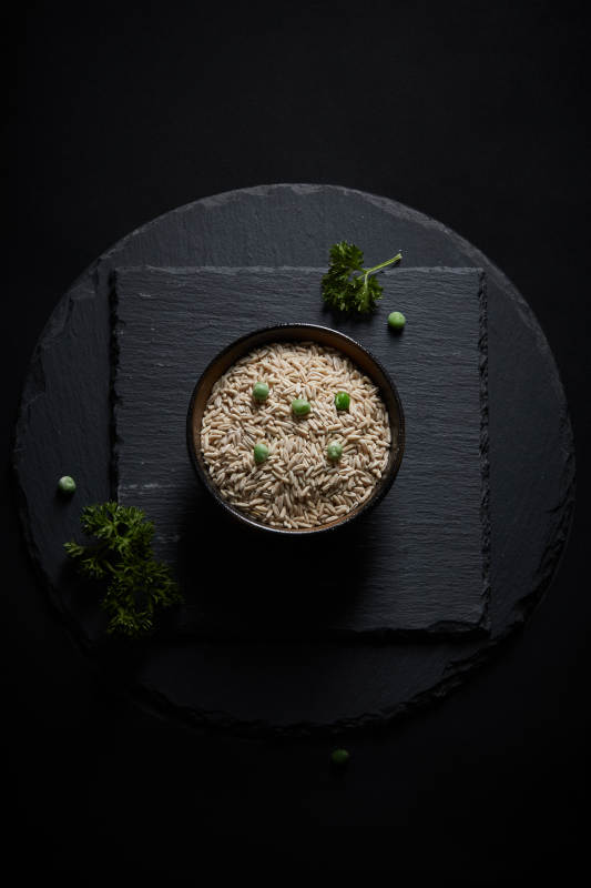 黑色青石板上的木质勺子装的燕麦米摆放在黑色背景中图片