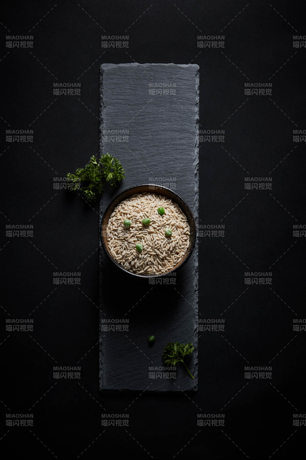 黑色青石板上的木质勺子装的燕麦米摆放在黑色背景中图片