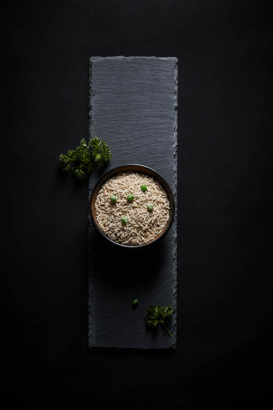 黑色青石板上的木质勺子装的燕麦米摆放在黑色背景中图片