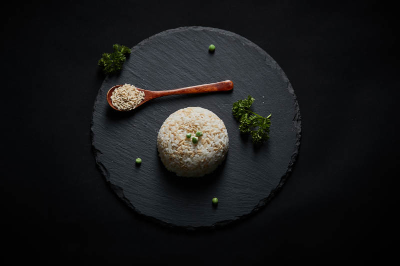 黑色青石板上摆放的燕麦米及蒸燕麦米饭图片