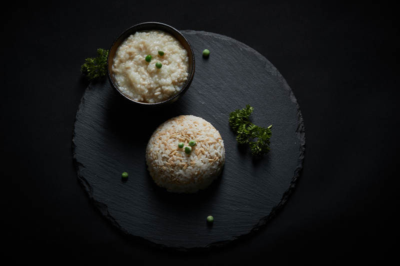 黑色青石板上摆放的燕麦米及蒸燕麦米饭图片