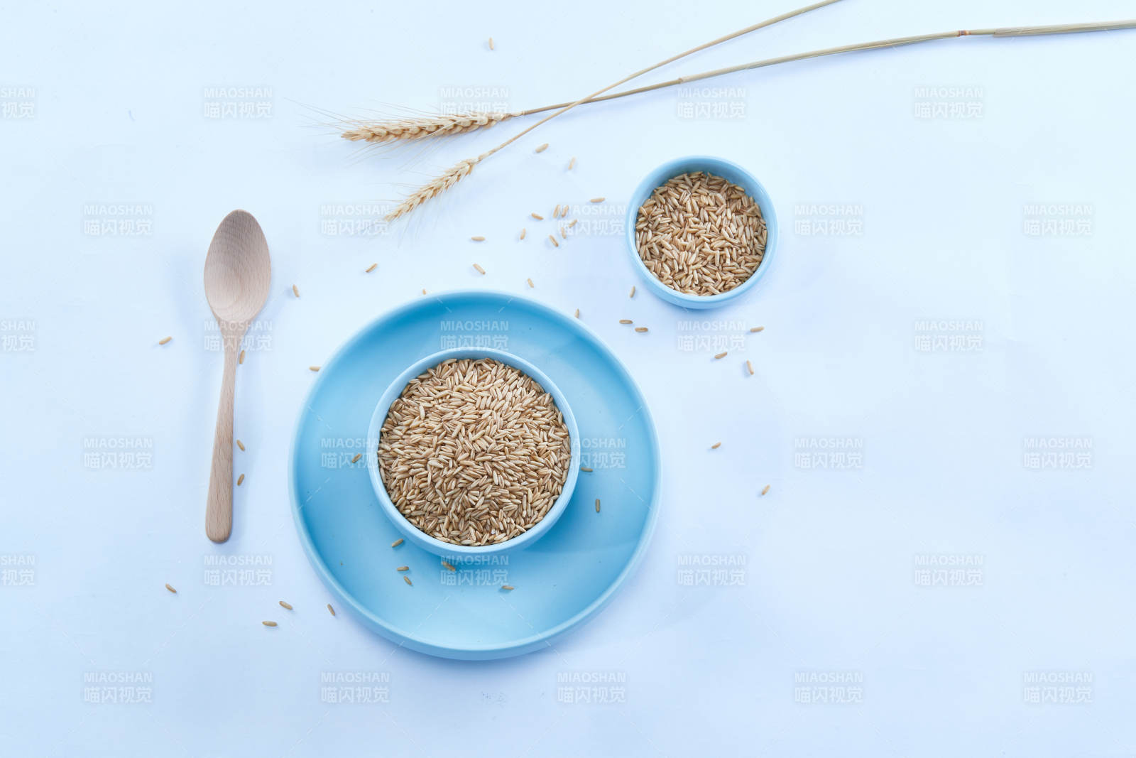 白色纸背景上的青釉瓷餐具及木质餐具装的燕麦米图片