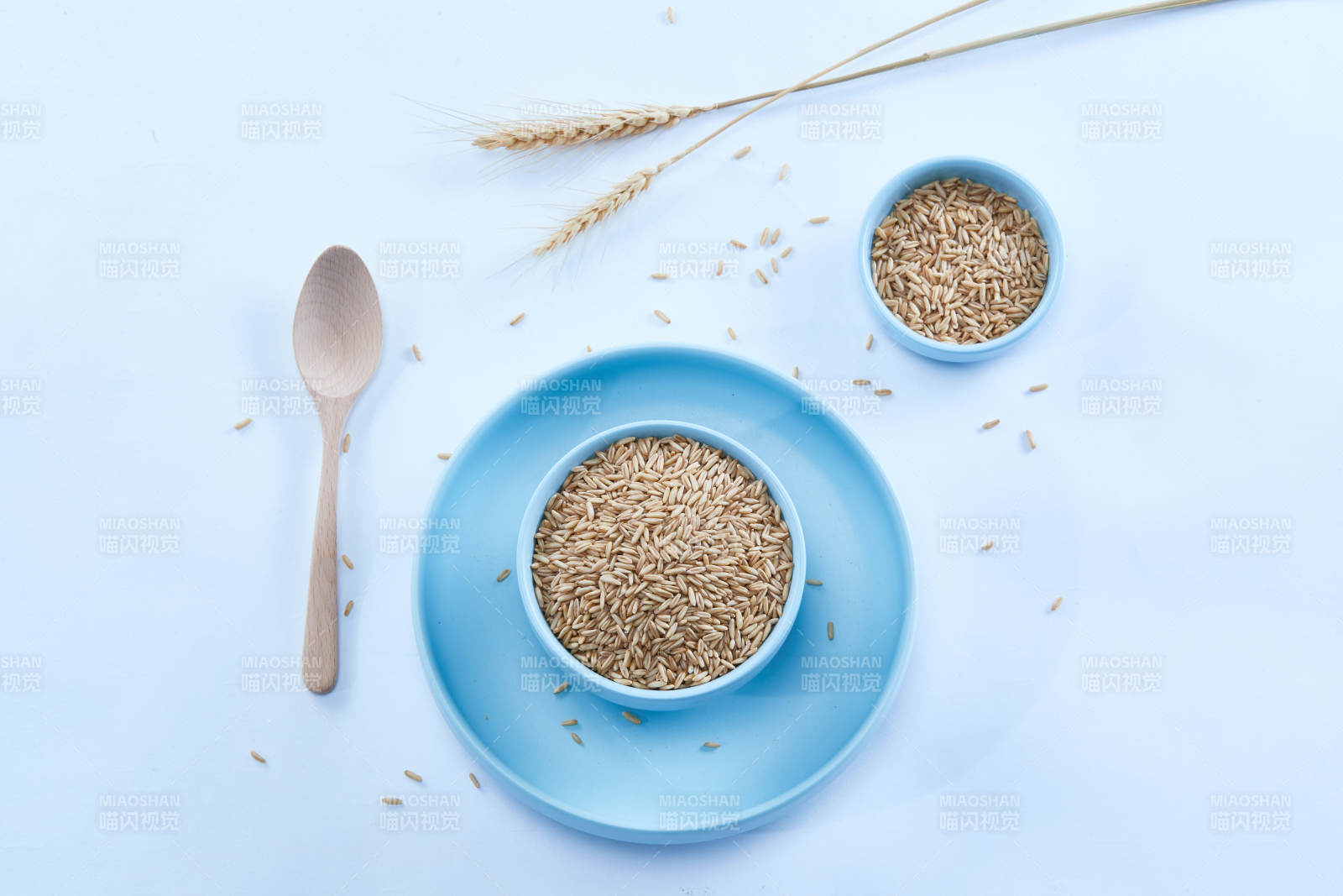 白色纸背景上的青釉瓷餐具及木质餐具装的燕麦米图片