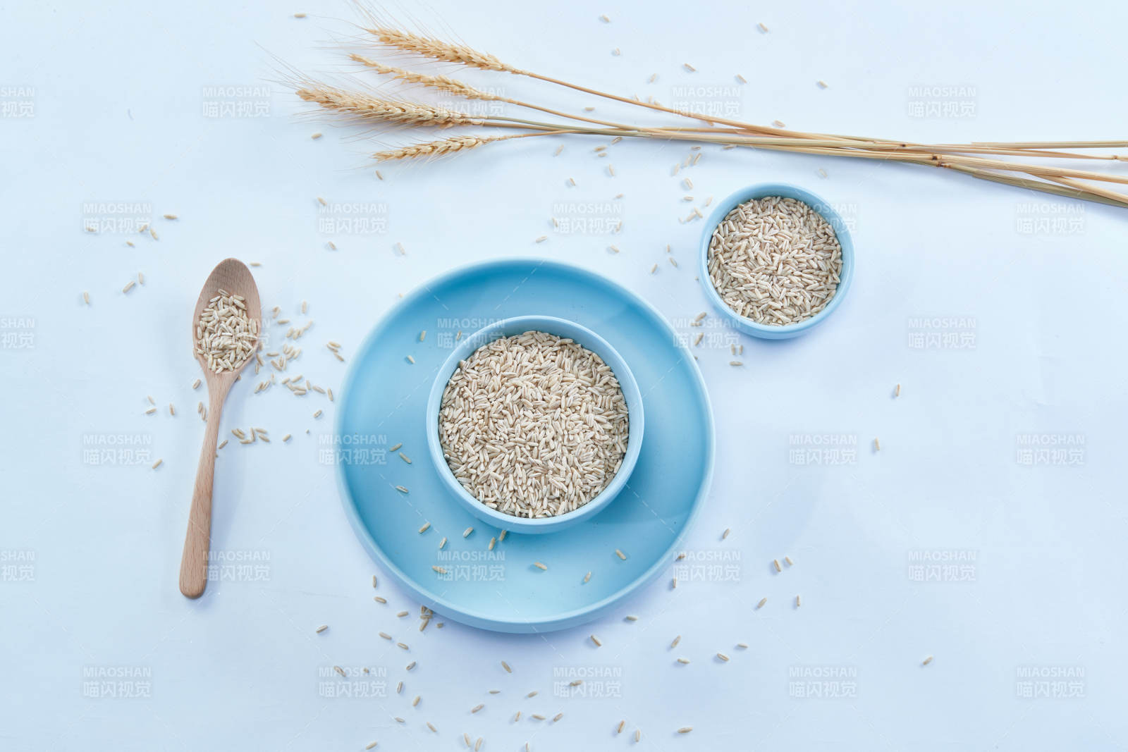 白色纸背景上的青釉瓷餐具及木质餐具装的燕麦米图片