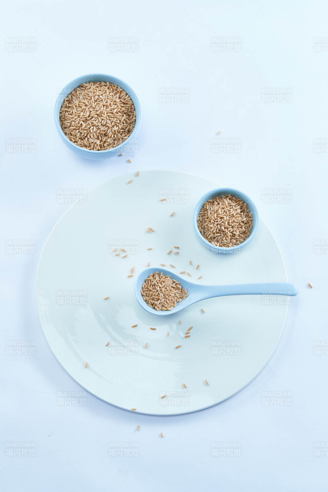 白色纸背景上的青釉瓷餐具及木质餐具装的燕麦米图片