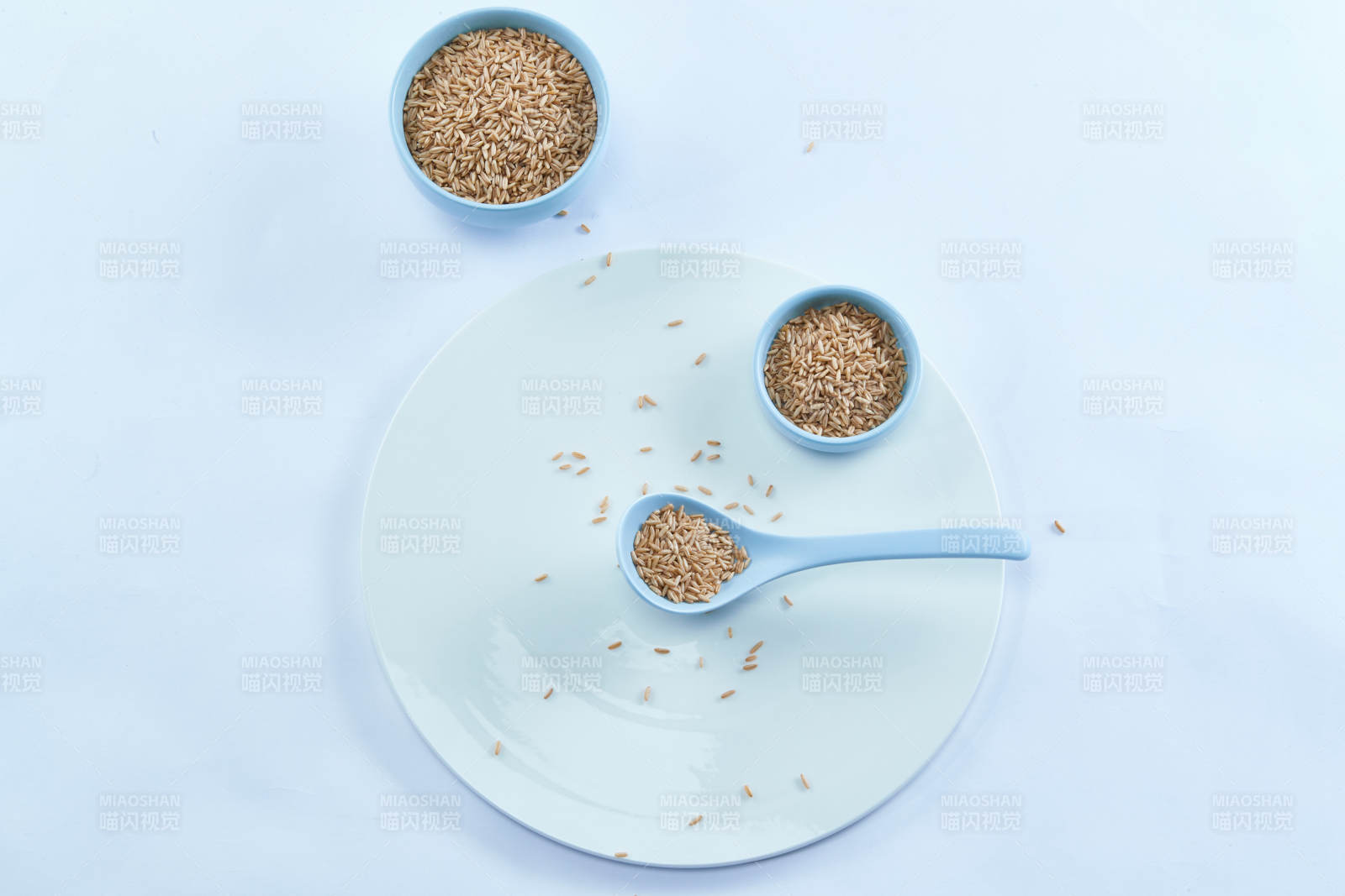 白色纸背景上的青釉瓷餐具及木质餐具装的燕麦米图片