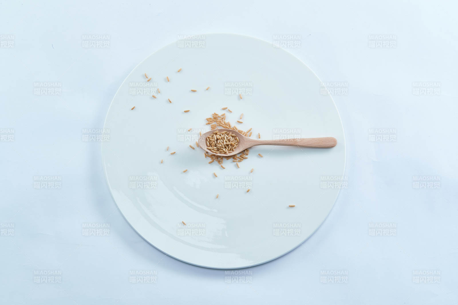 白色纸背景上的青釉瓷餐具及木质餐具装的燕麦米图片