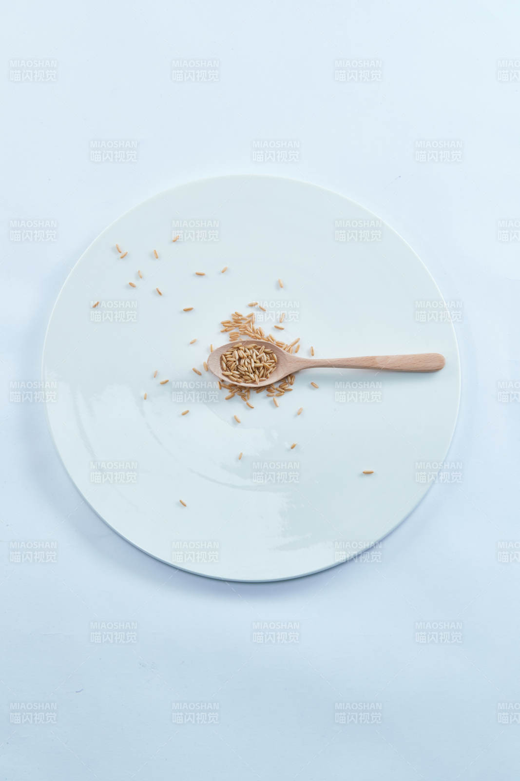 白色纸背景上的青釉瓷餐具及木质餐具装的燕麦米图片