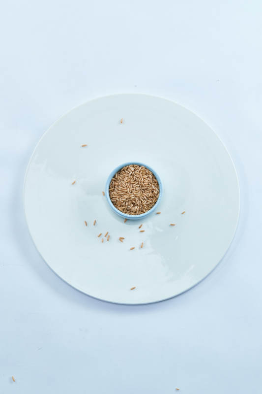 白色纸背景上的青釉瓷餐具及木质餐具装的燕麦米图片