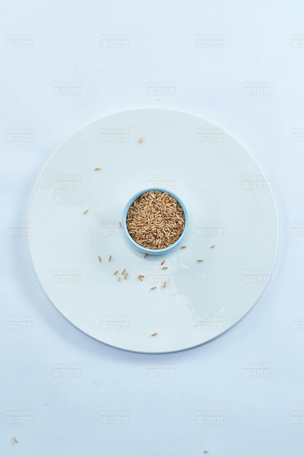 白色纸背景上的青釉瓷餐具及木质餐具装的燕麦米图片