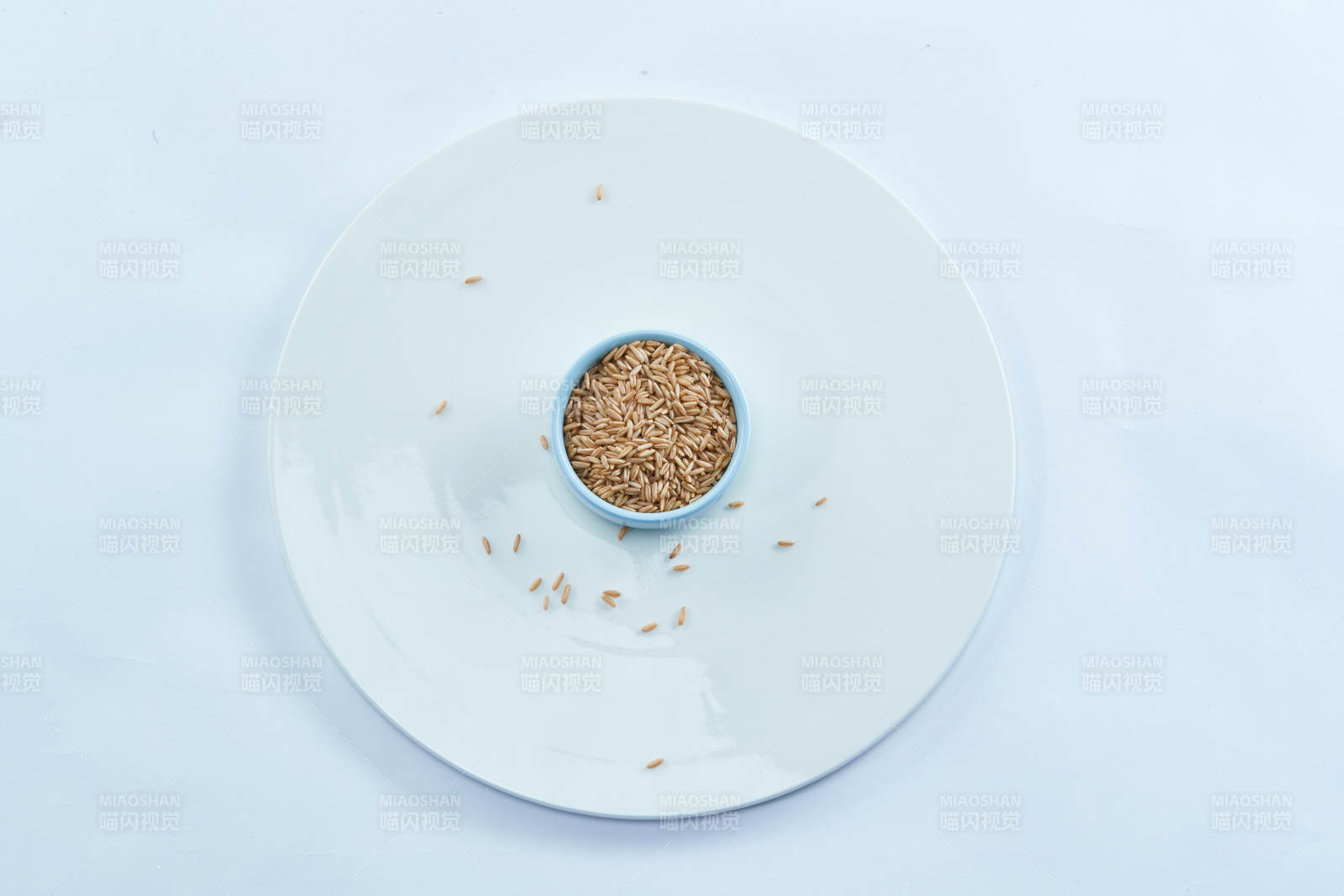 白色纸背景上的青釉瓷餐具及木质餐具装的燕麦米图片