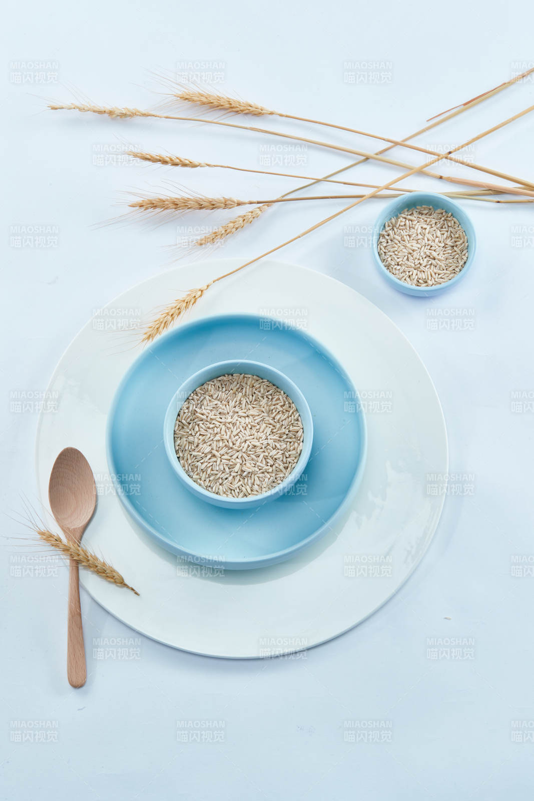 白色纸背景上的青釉瓷餐具及木质餐具装的燕麦米图片