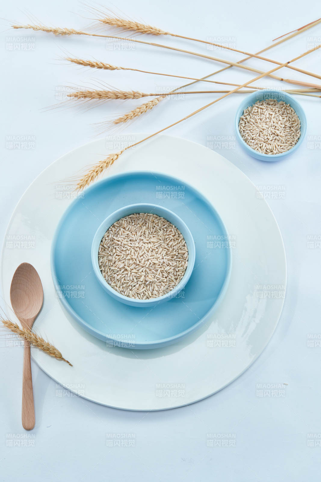 白色纸背景上的青釉瓷餐具及木质餐具装的燕麦米图片