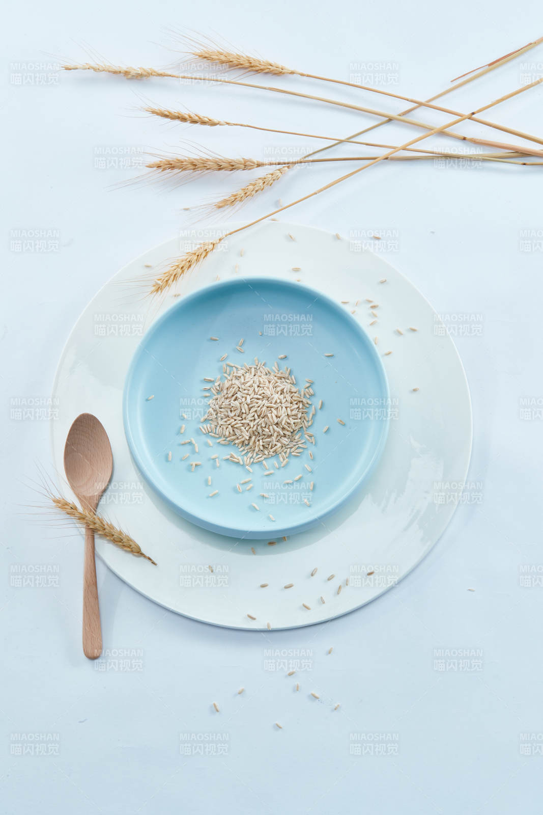 白色纸背景上的青釉瓷餐具及木质餐具装的燕麦米图片