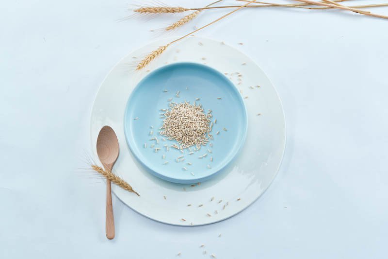 白色纸背景上的青釉瓷餐具及木质餐具装的燕麦米图片