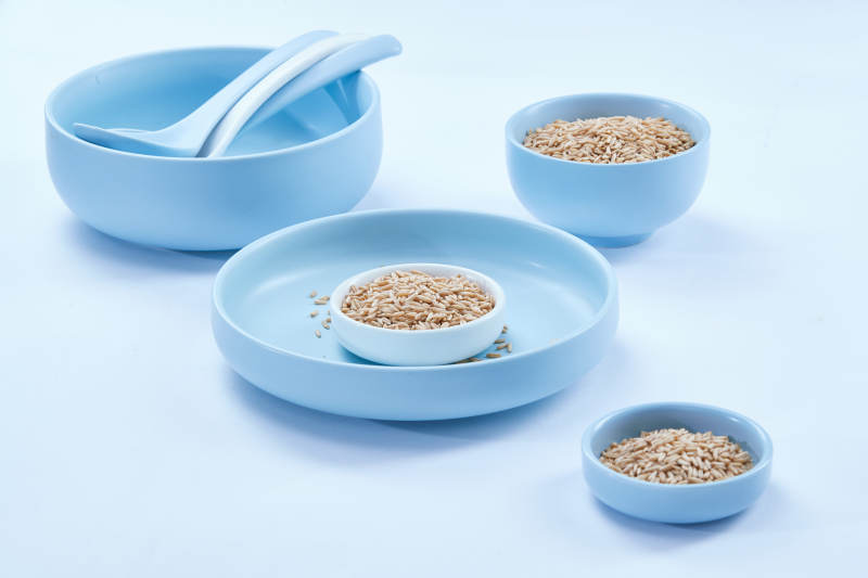 白色纸背景上的青釉瓷餐具及木质餐具装的燕麦米图片