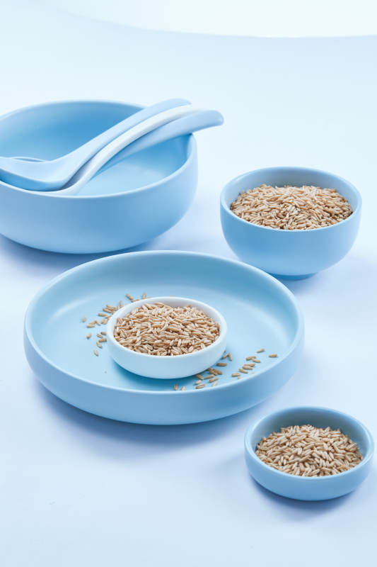 白色纸背景上的青釉瓷餐具及木质餐具装的燕麦米图片