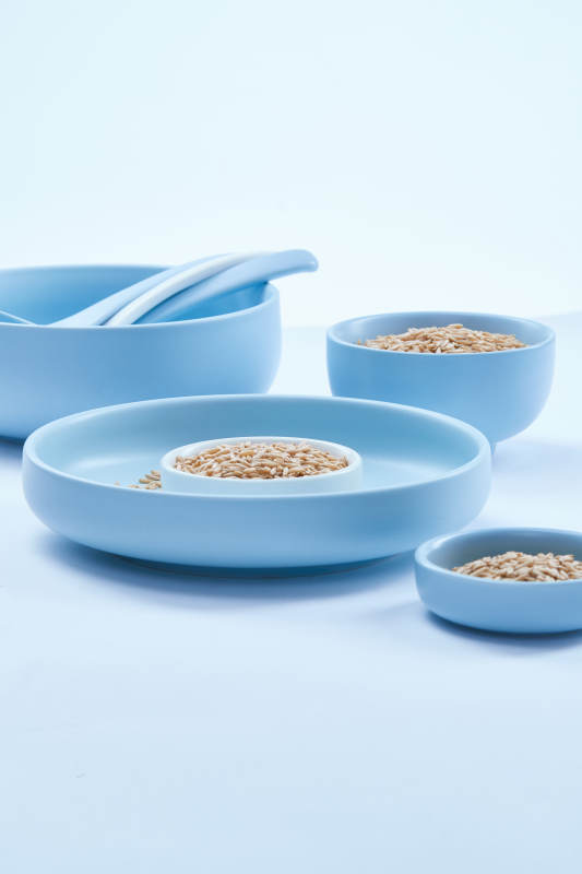 白色纸背景上的青釉瓷餐具及木质餐具装的燕麦米图片