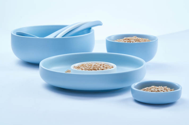 白色纸背景上的青釉瓷餐具及木质餐具装的燕麦米图片