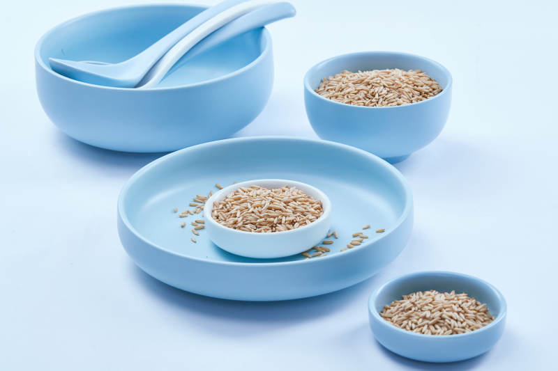 白色纸背景上的青釉瓷餐具及木质餐具装的燕麦米图片