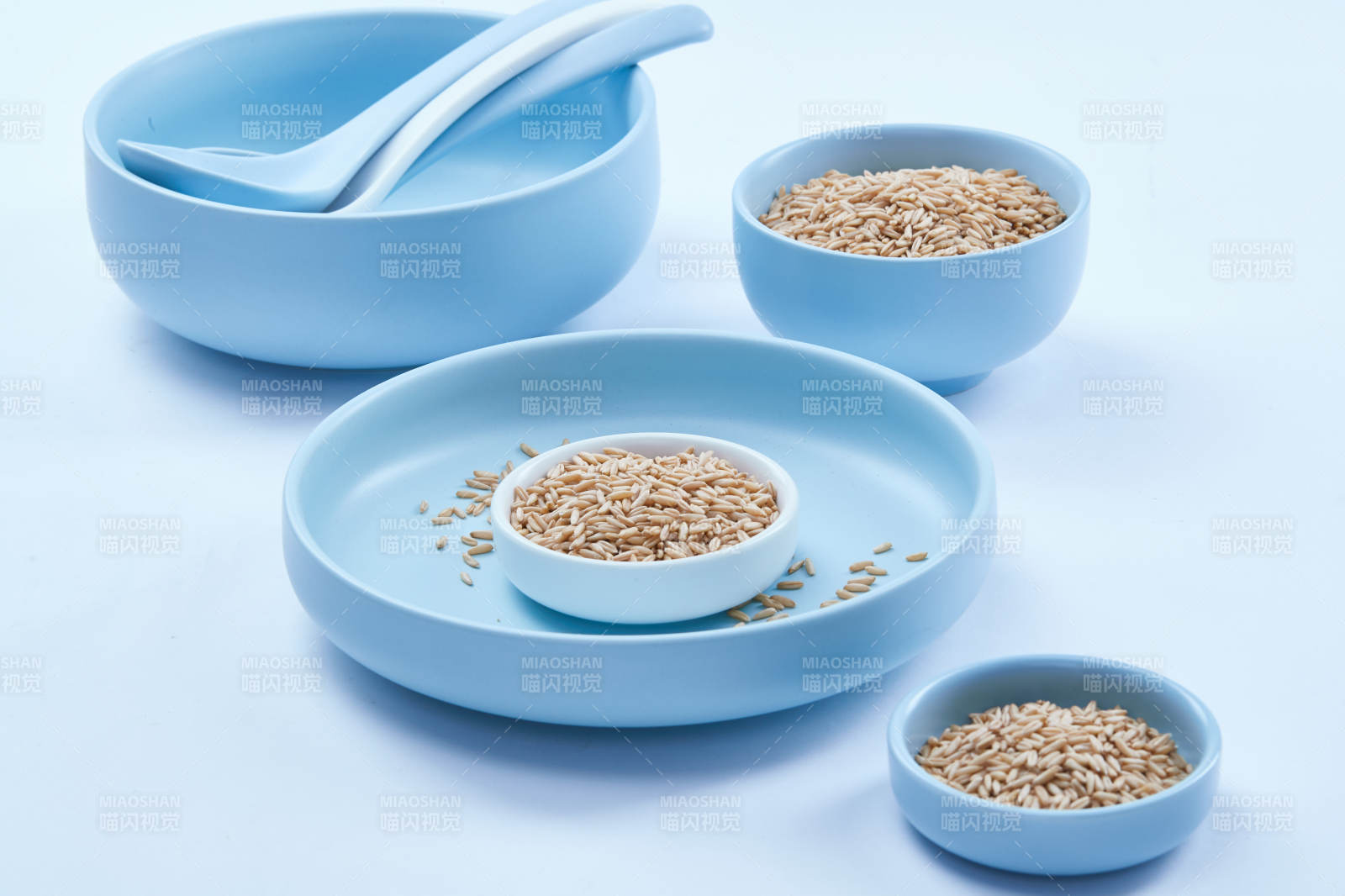 白色纸背景上的青釉瓷餐具及木质餐具装的燕麦米图片