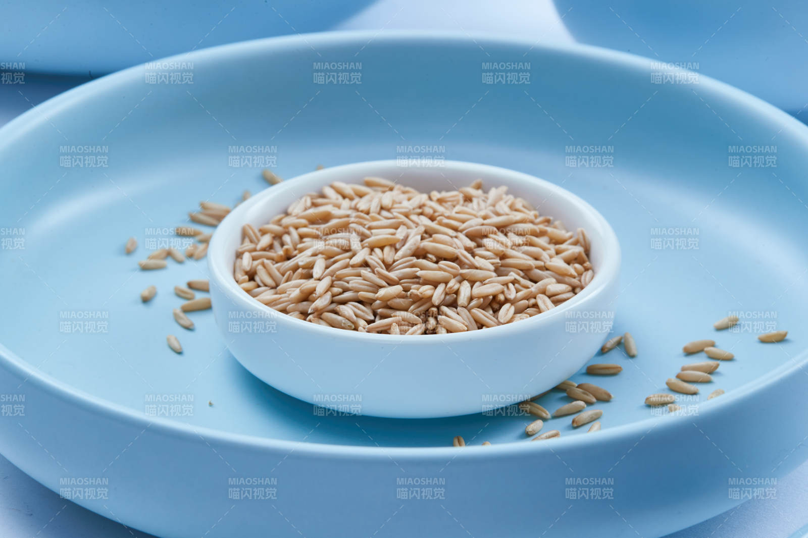 白色纸背景上的青釉瓷餐具及木质餐具装的燕麦米图片