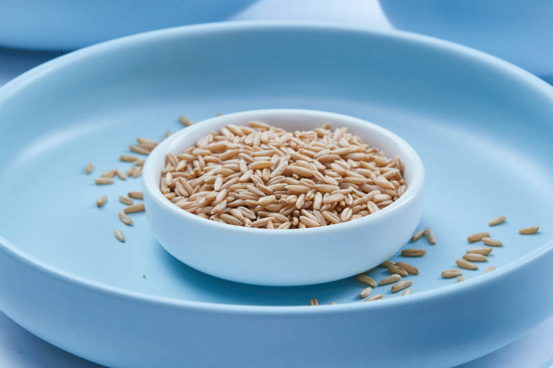 白色纸背景上的青釉瓷餐具及木质餐具装的燕麦米图片