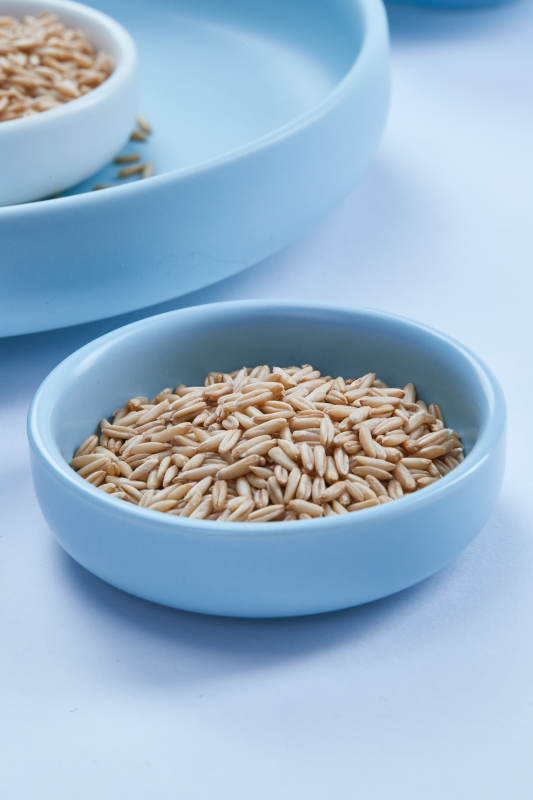 白色纸背景上的青釉瓷餐具及木质餐具装的燕麦米图片