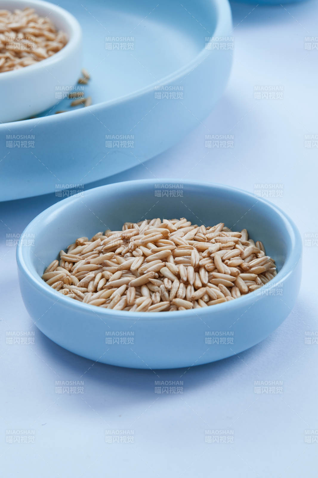 白色纸背景上的青釉瓷餐具及木质餐具装的燕麦米图片