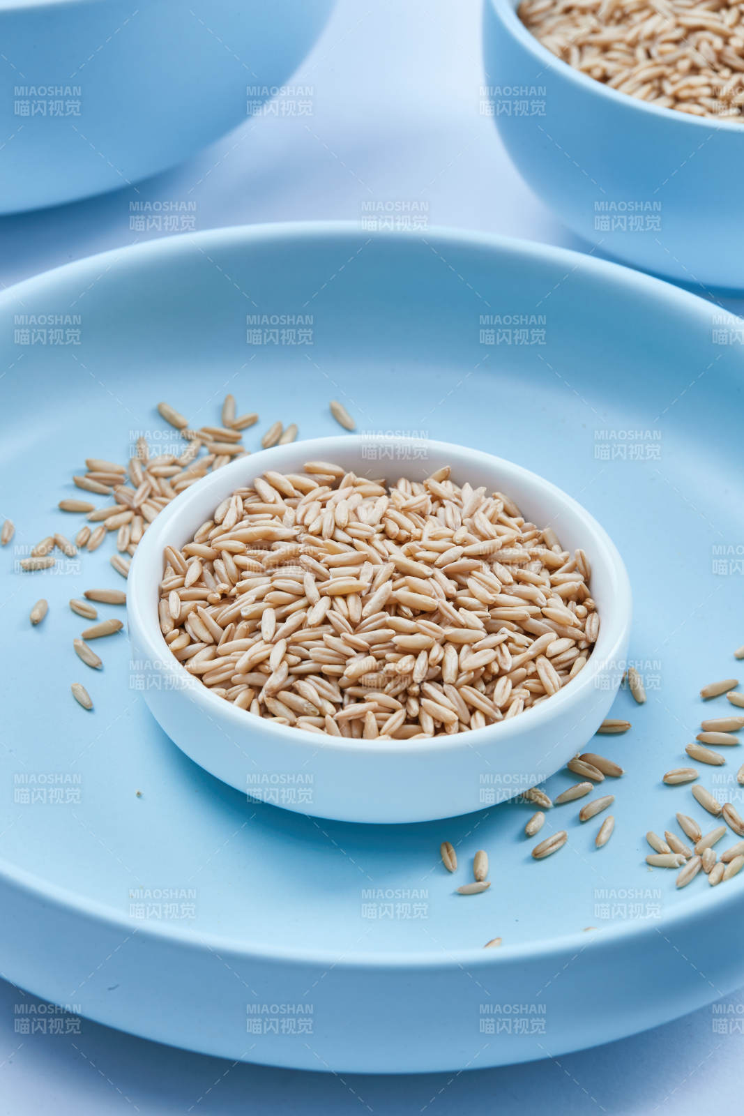 白色纸背景上的青釉瓷餐具及木质餐具装的燕麦米图片